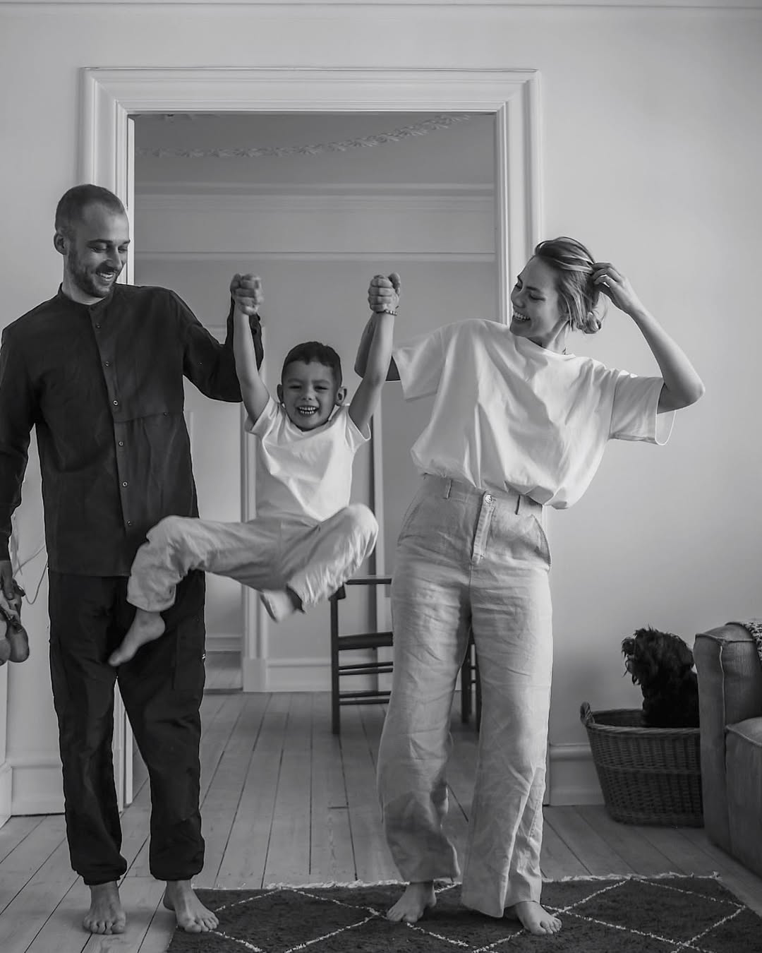 Black and white photo of a family with a child in a living room.