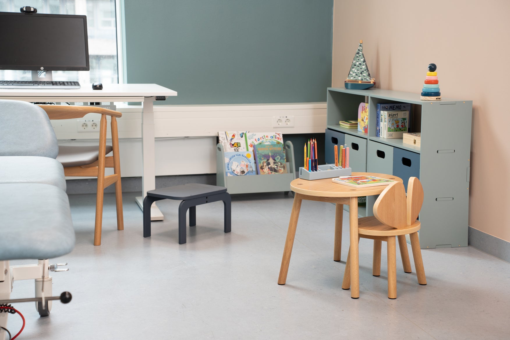 Modern classroom with wooden table and chairs, bookshelf, and chalkboard.