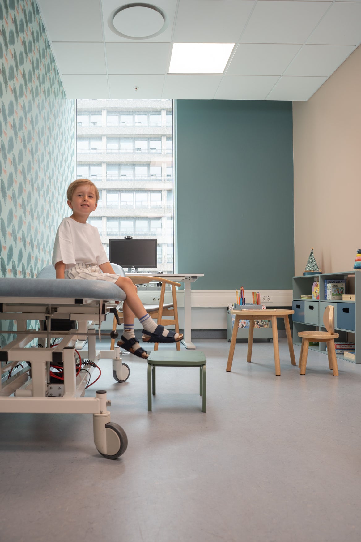 Child in a hospital room with medical equipment and furniture.
