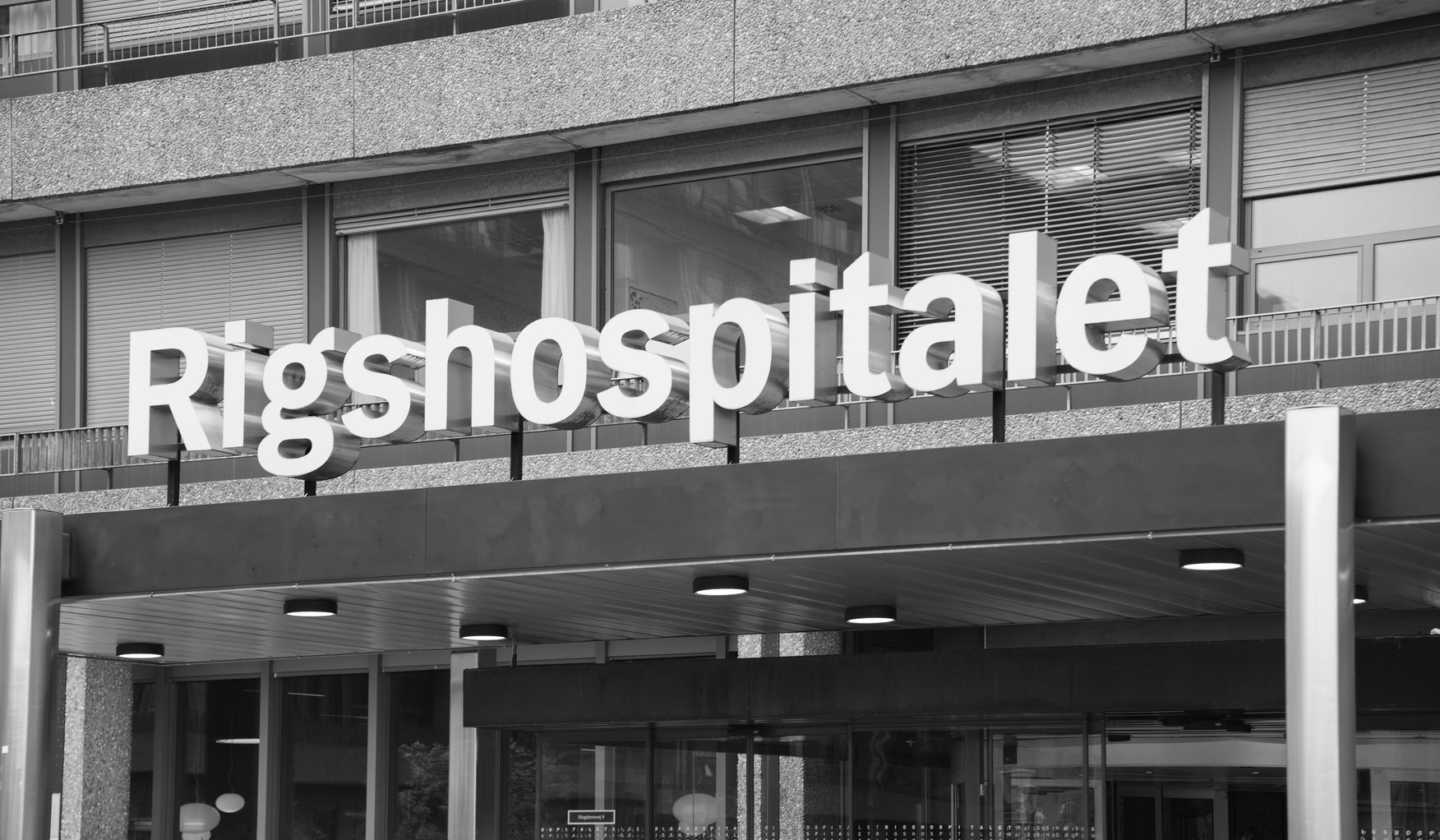 Black and white photo of a hospital entrance with 'Rigshospitalet' sign.