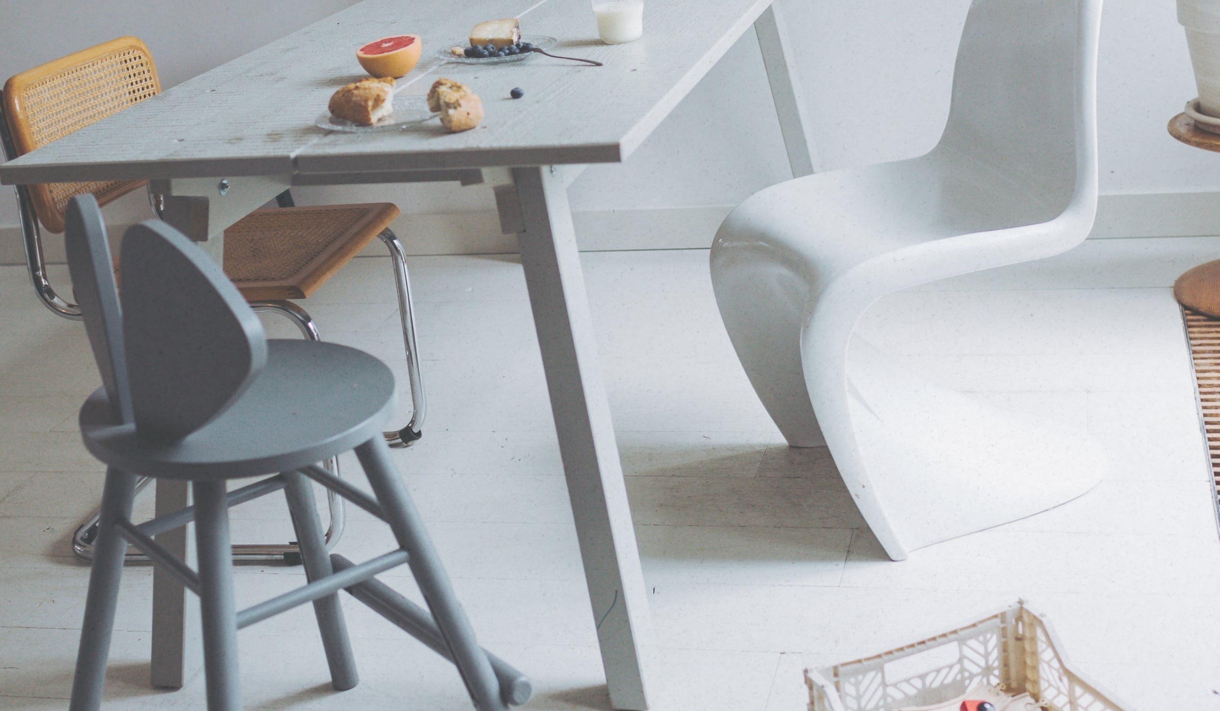 Dining area with a table, chairs, and a basket on a light wooden floor.