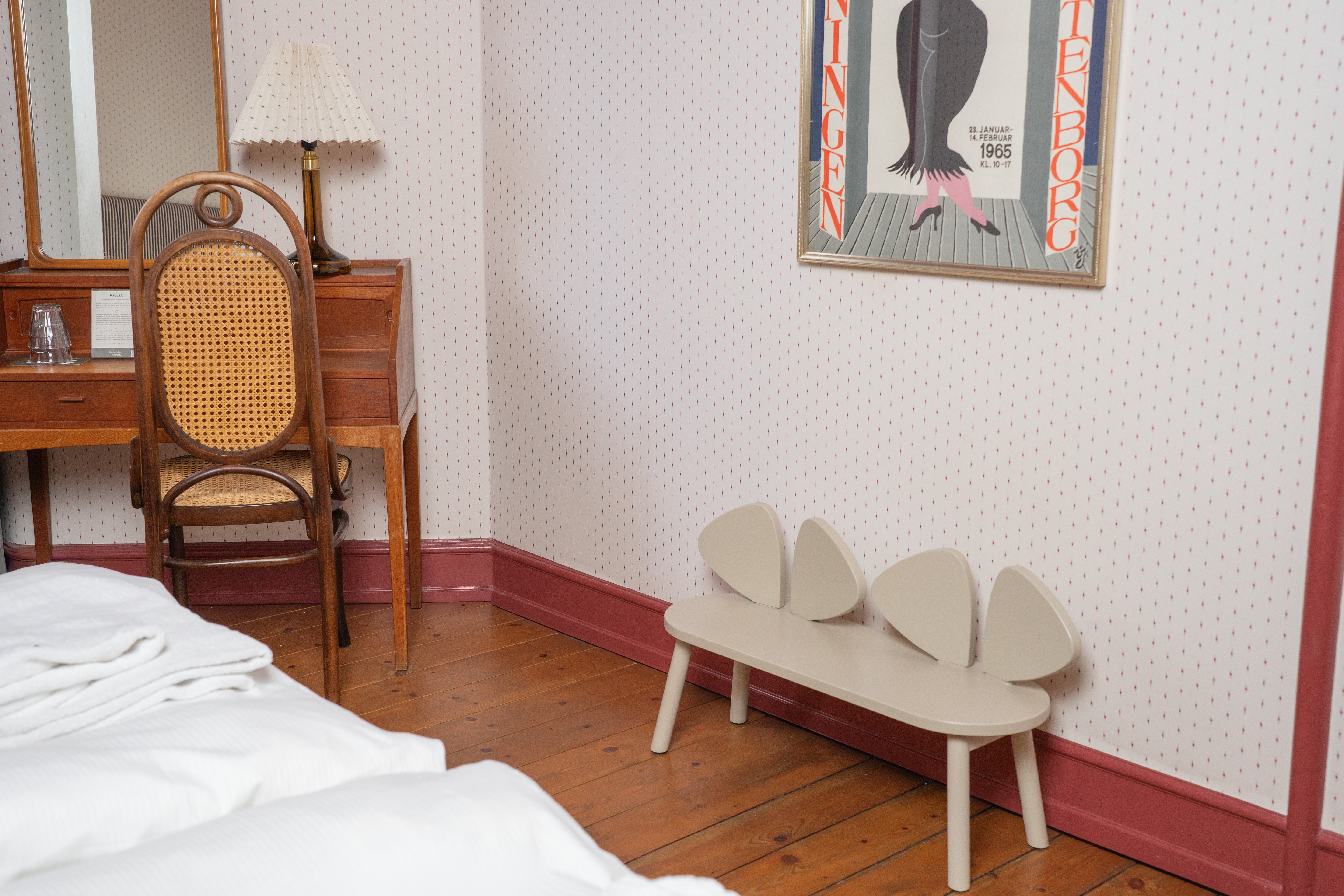 Room interior with a bed, wooden desk, chair, and wall art.