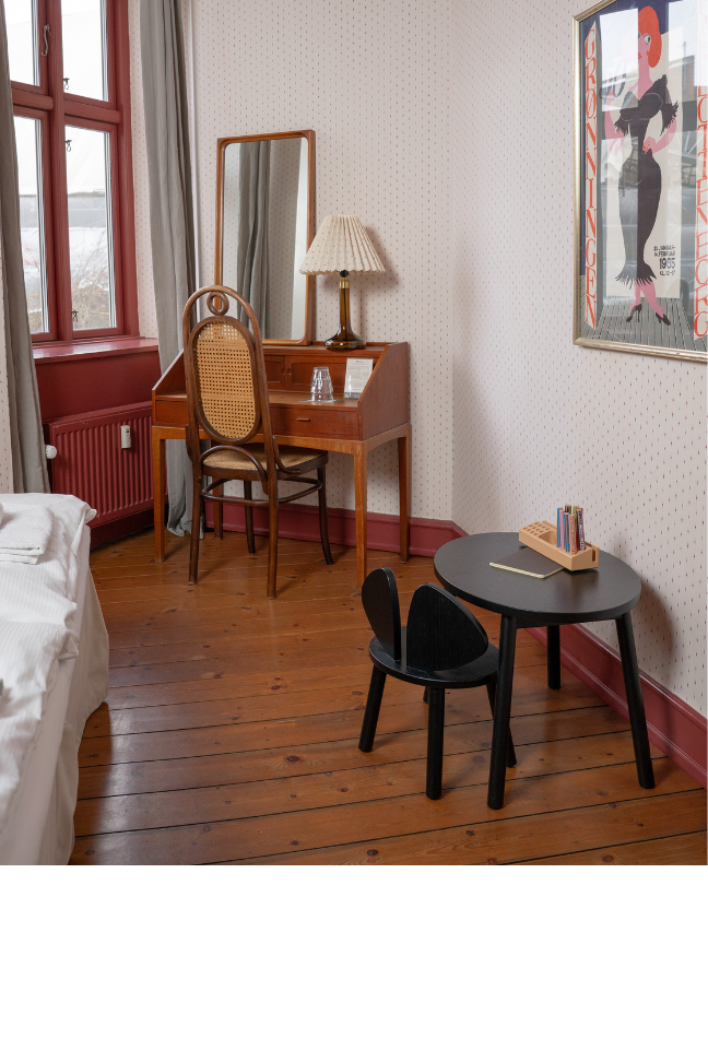 a room with wooden floors and red walls, with a kids black table and chair set