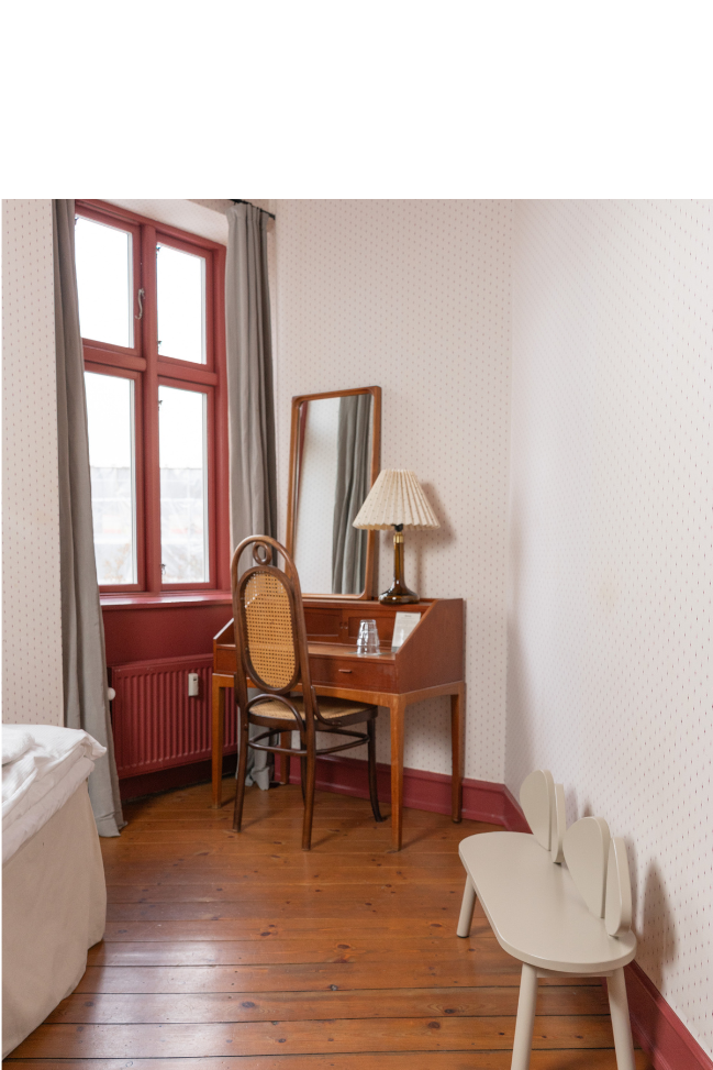 a room with wooden floors and red walls with a kids' bench in beige