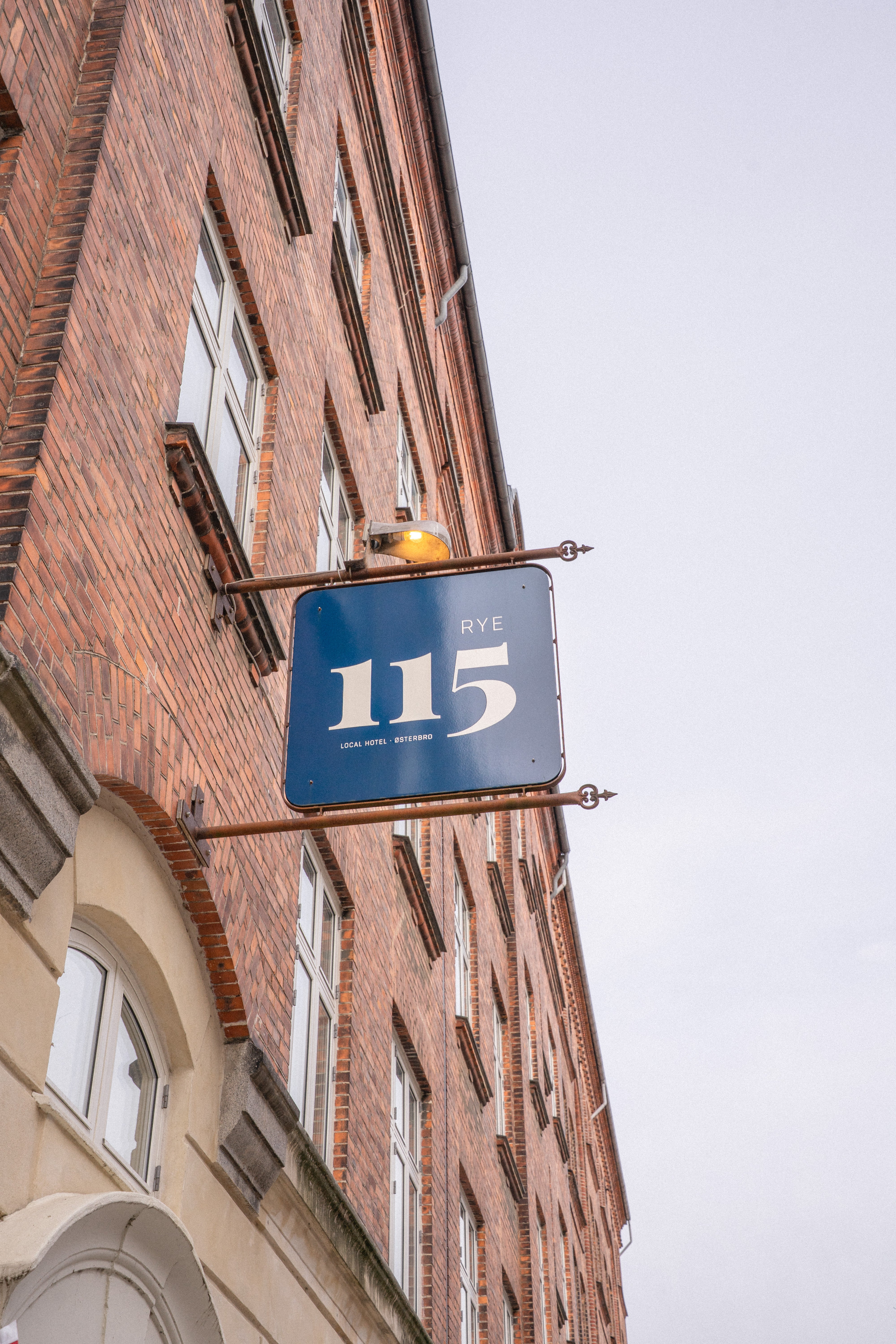 Building facade with a sign displaying the number 115 against a clear sky.
