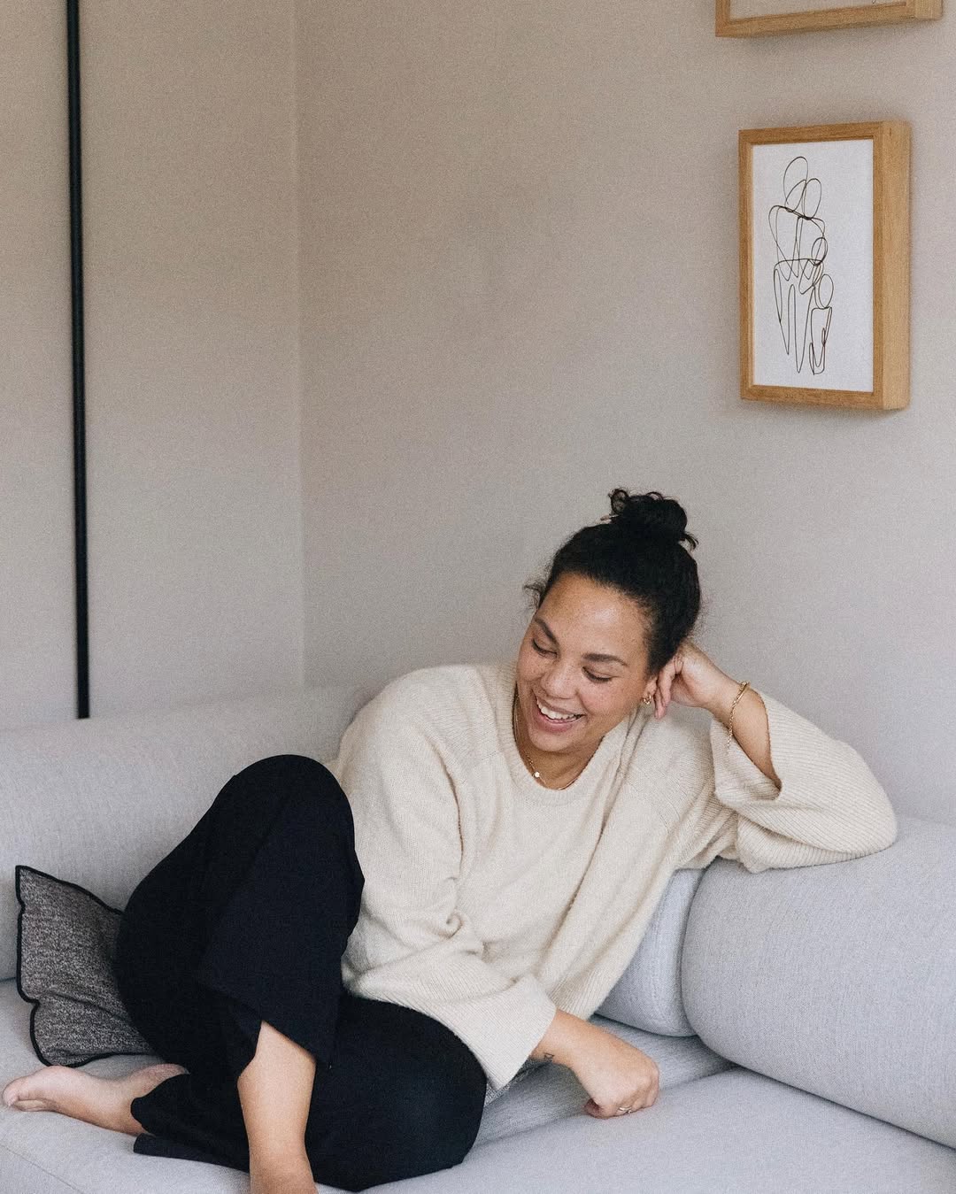 Woman sitting on a couch in a modern living room with minimal decor.