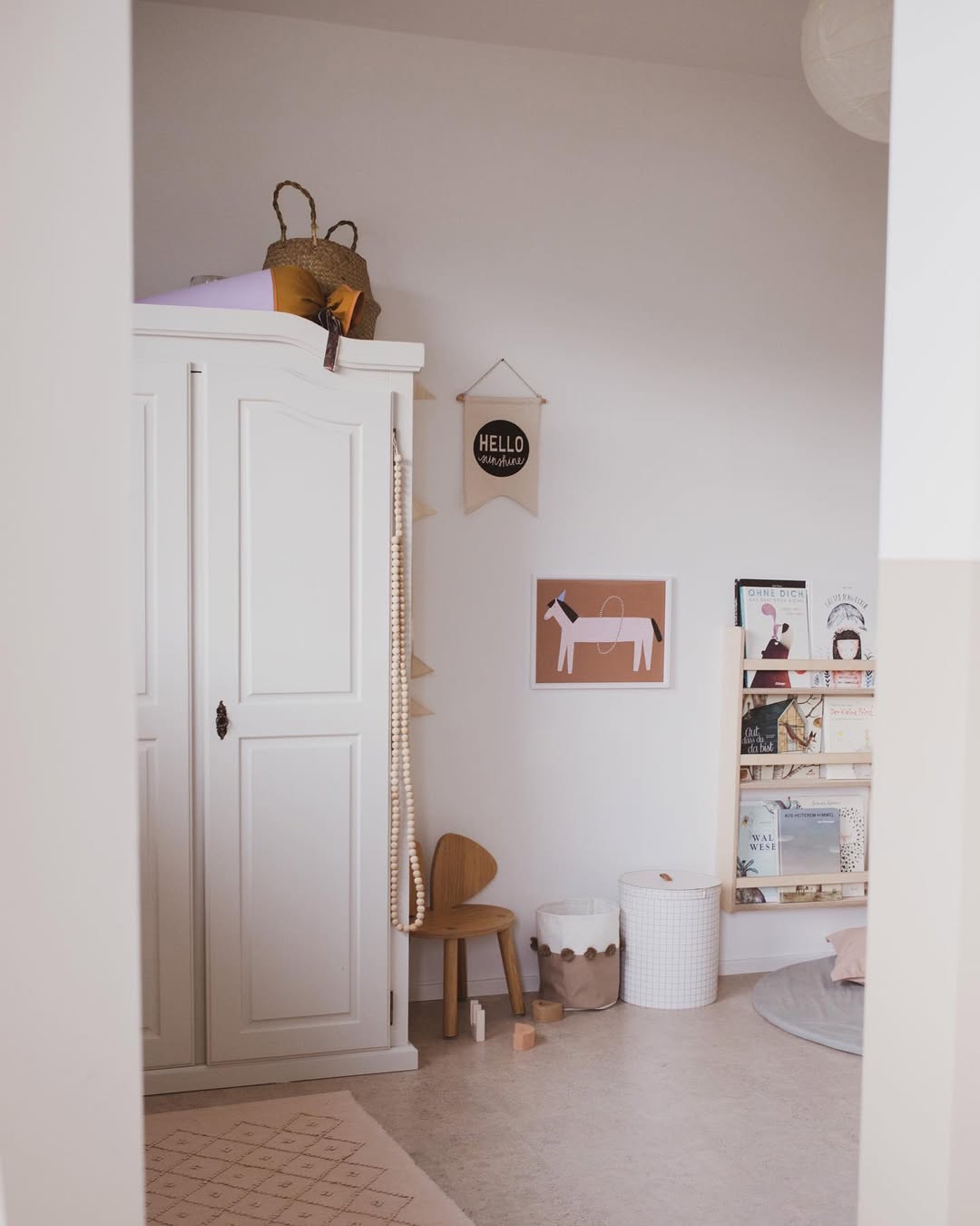 Children's room with white wardrobe, wooden chair, and wall decorations.