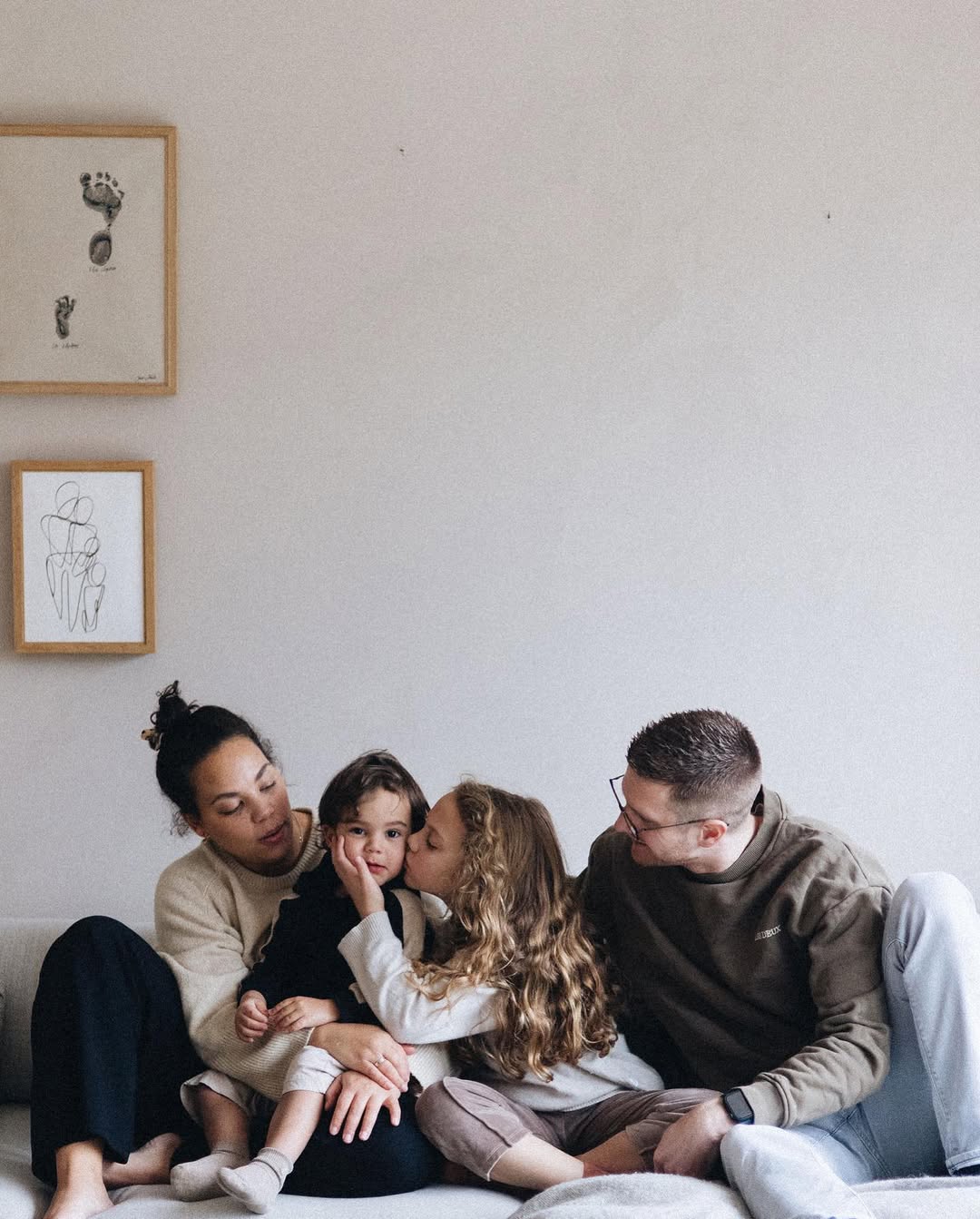 Family of four sitting together on a couch in a cozy living room.