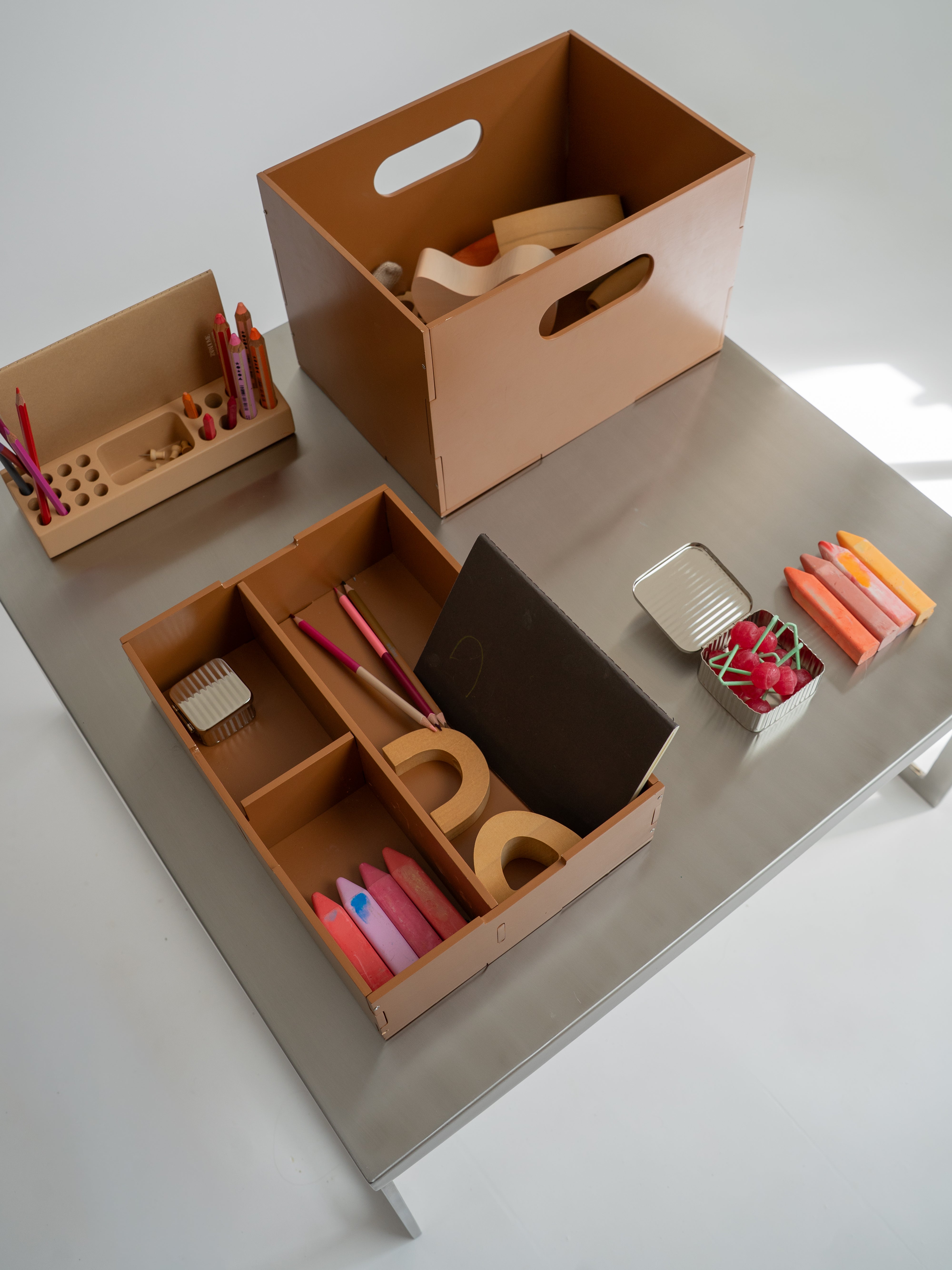 Collection of wooden toys and storage boxes on a light gray surface.