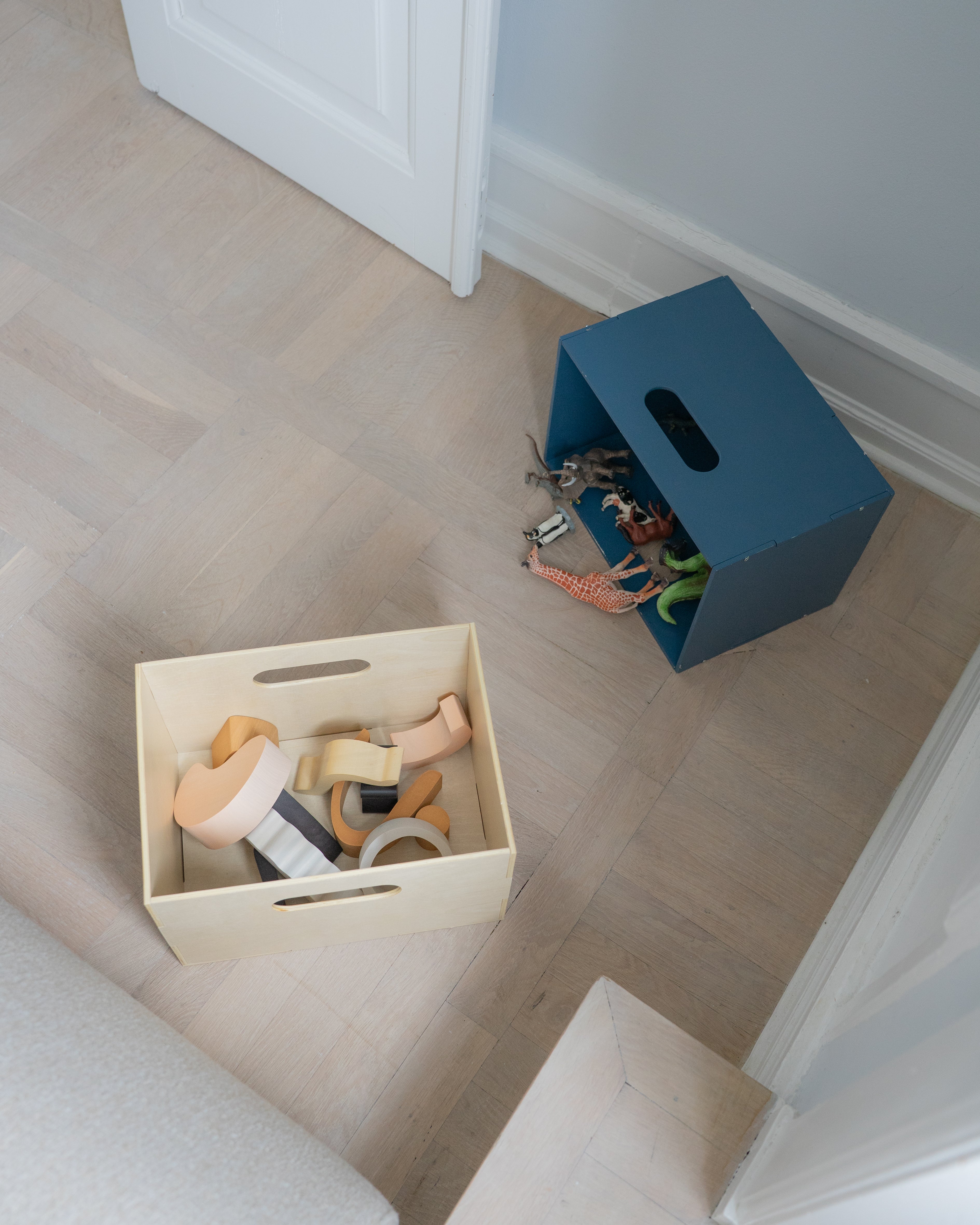 Two storage boxes with toys on a wooden floor.