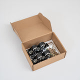 An open brown cardboard box containing four black caster wheels with metal axles and a small clear bag of hardware, photographed on a clean light gray studio background.