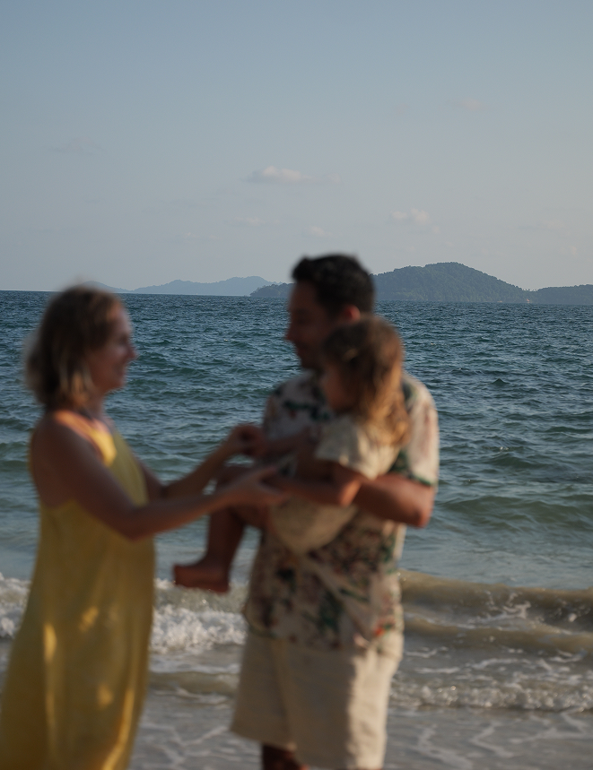 Two people standing on a beach with ocean and sky in the background