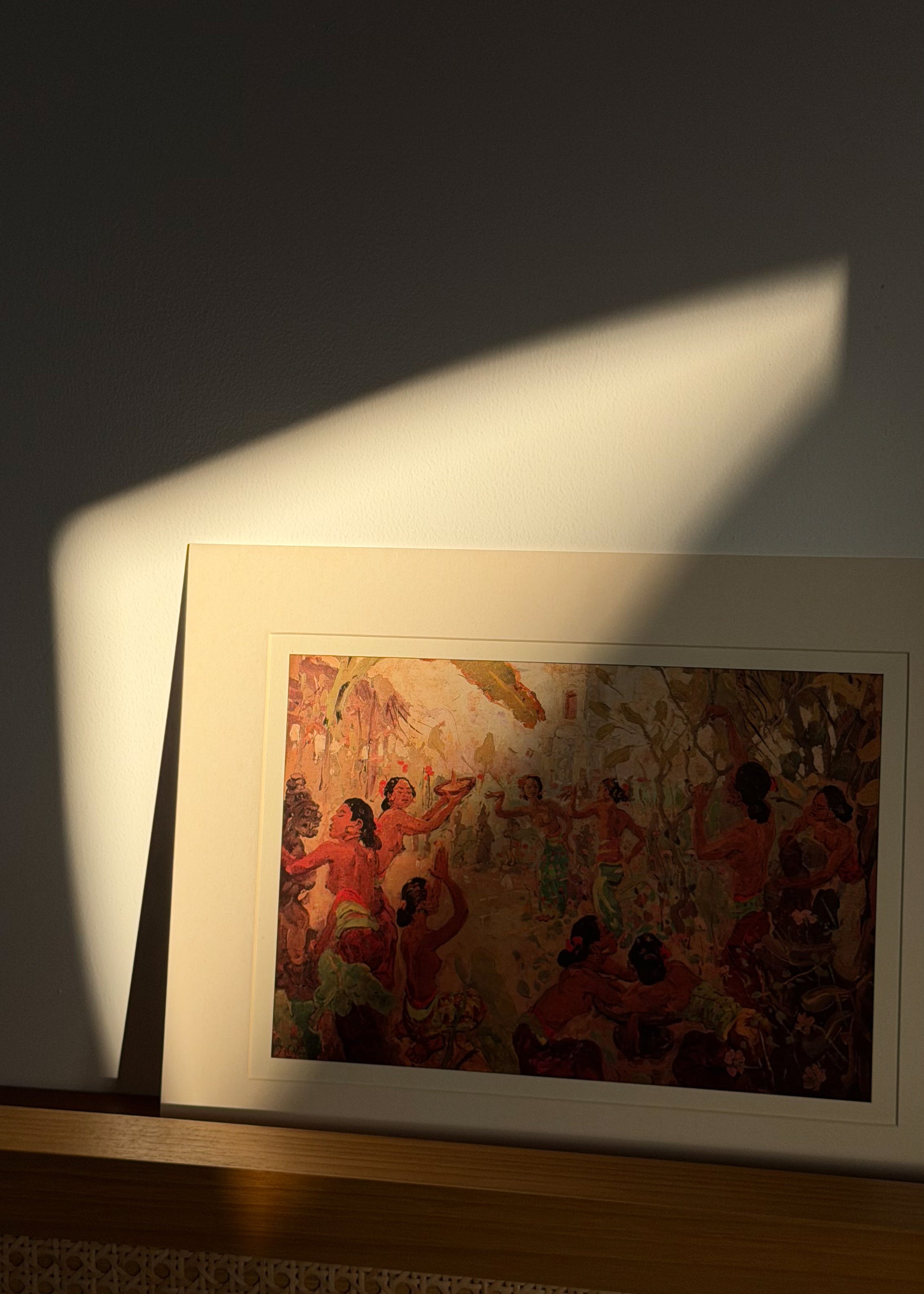 Framed artwork on a wall with a soft light casting a shadow
