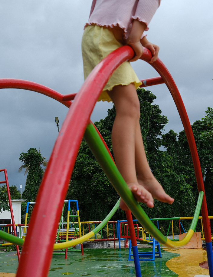 Child playing on a playground structure with trees in the background